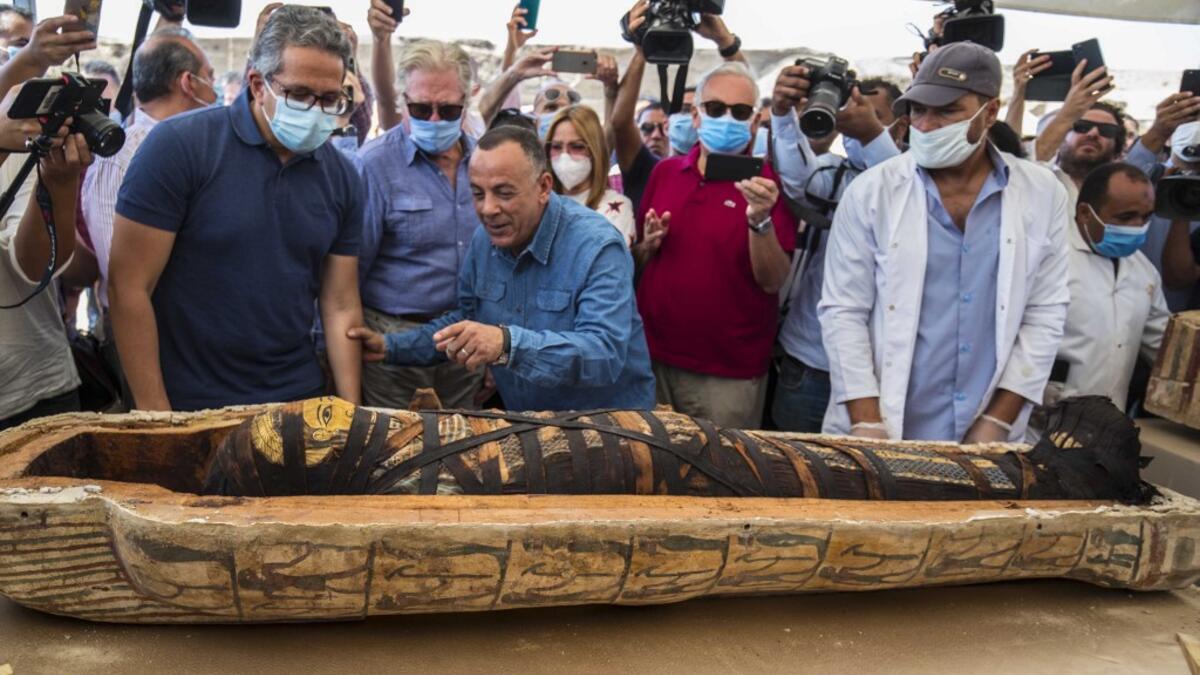 A picture taken on October 3, 2020 shows Egyptian Minister of Tourism and Antiquities Khaled Al-Anani (L), and Mustafa Waziri (R), Secretary General of the Supreme Council of Antiquities, unveil the mummy inside a sarcophagus excavated by the Egyptian archaeological mission working at the Saqqara necropolis, 30 kms south of the capital Cairo, which resulted in the discovery of a deep burial well with more than 59 human coffins closed for more than 2,500 years. They were unearthed south of Cairo in the spraw