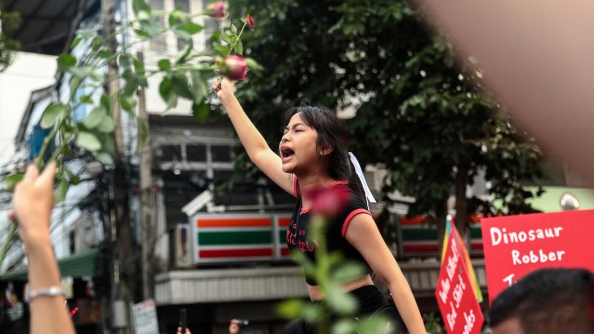 A pro-democracy protester holds up flowers while shouting slogans during an anti-government rally in Bangkok on October 14, 2020. Jack TAYLOR / AFP