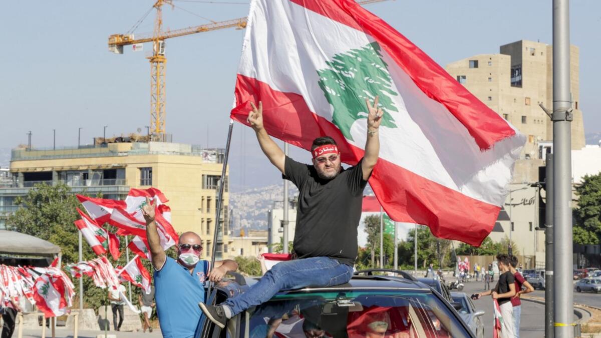 Lebanese demonstrators wave the national flag as they drive to a demonstration, marking the first anniversary of a non-sectarian protest movement, in the capital Beirut's downtown area on October 17, 2020. ANWAR AMRO / AFP