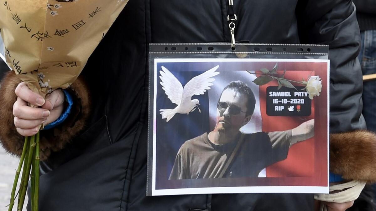 A woman holds a picture of Samuel Paty, Place de la Liberte in Lille on October 18, 2020, in homage to the history teacher, two days after he was beheaded by an attacker who was shot dead by policemen. FRANCOIS LO PRESTI / AFP
