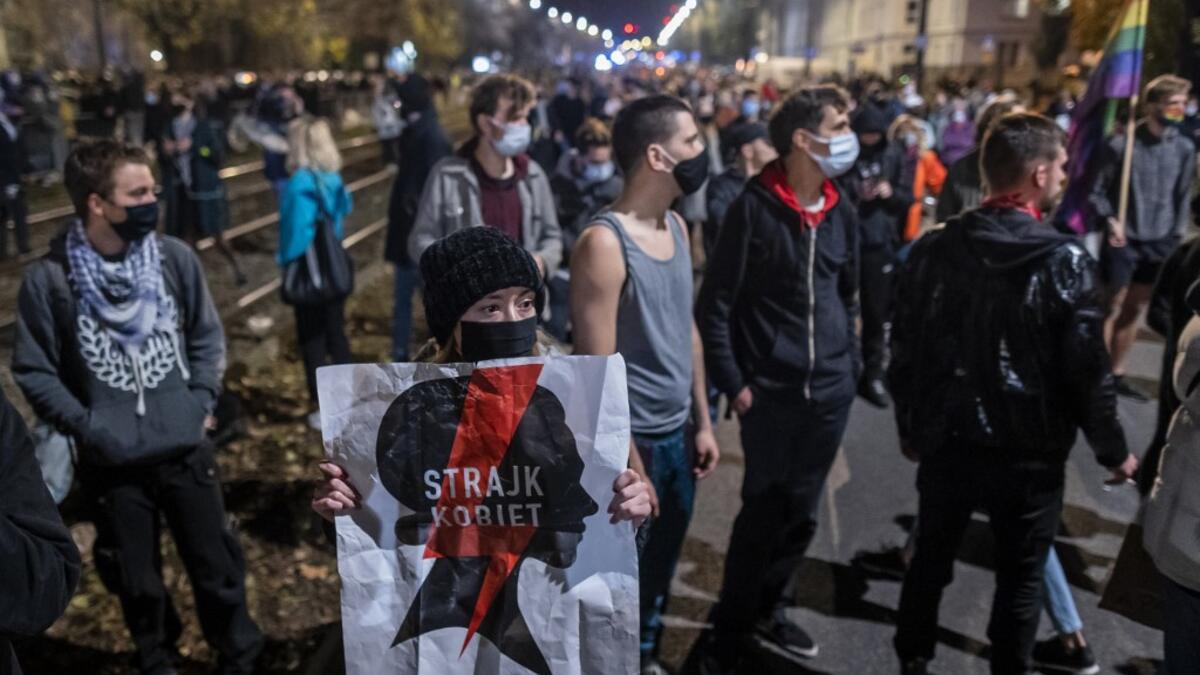 A woman holds a banner reading "Strajk Kobiet" (Women's Strike) in front of the house of Jaroslaw Kaczynski, leader of Poland's ruling Law and Justice party (PIS), during a demonstration against a decision by the Constitutional Court on abortion law restriction, Warsaw, October 23, 2020, in Warsaw on October 23, 2020. Wojtek RADWANSKI / AFP