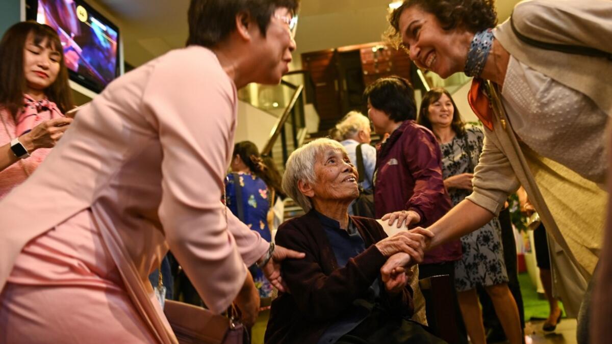 This photograph taken on October 22, 2020 shows guests greeting 89-year-old Vietnamese artist Mong Bich during the opening of her first solo exhibition at the French Cultural Centre in Hanoi. Bich specialises in silk paintings of daily life and ordinary people, women in particular, and ploughed a lonely furrow during many years of war when artists were steered towards the army or frontline workers as subjects. Manan VATSYAYANA / AFP