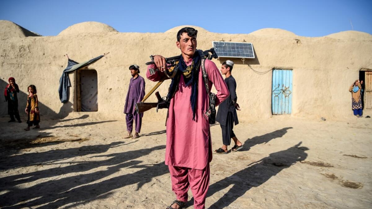 In this photo taken on September 27, 2020, a policeman (C) holding weapons stands guard in the courtyard of a house at Deh Qubad village in Maiwand district of Kandahar province. The dry and dusty village of Aziz Abad in Maiwand district sits on the frontline of Afghanistan's war and is currently under government control -- but only just. WAKIL KOHSAR / AFP