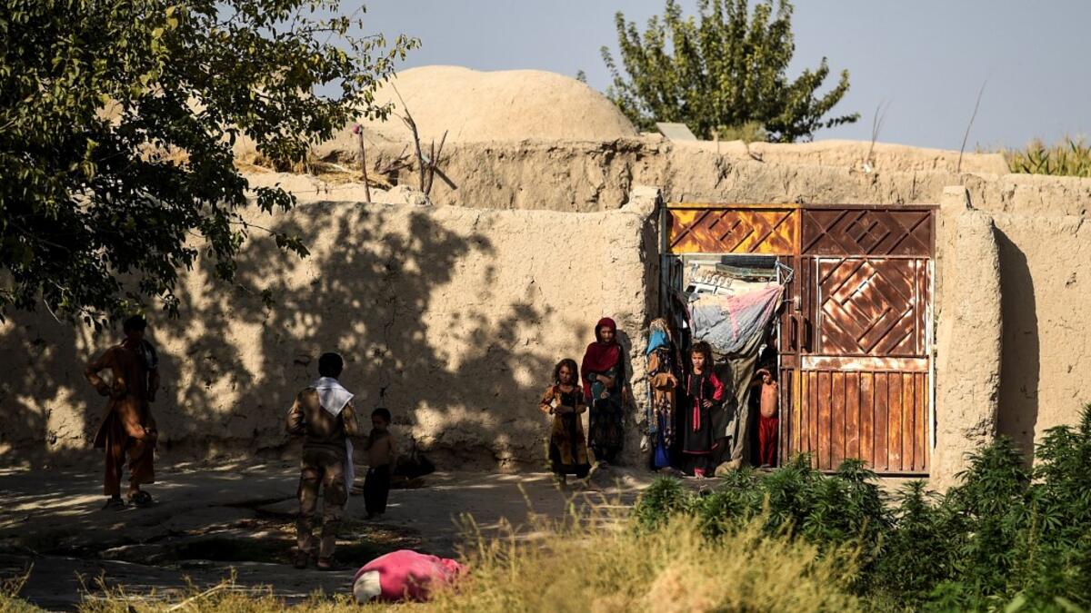 In this photo taken on September 27, 2020, children gather at the entrance of a house at Deh Qubad village in Maiwand district of Kandahar province. The dry and dusty village of Aziz Abad in Maiwand district sits on the frontline of Afghanistan's war and is currently under government control -- but only just. WAKIL KOHSAR / AFP