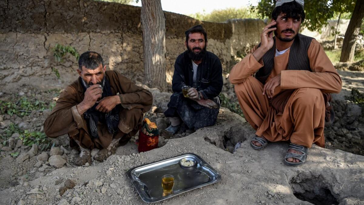 In this photo taken on September 27, 2020, labourers take a rest as they drink tea at Deh Qubad village in Maiwand district of Kandahar province. The dry and dusty village of Aziz Abad in Maiwand district sits on the frontline of Afghanistan's war and is currently under government control -- but only just. WAKIL KOHSAR / AFP