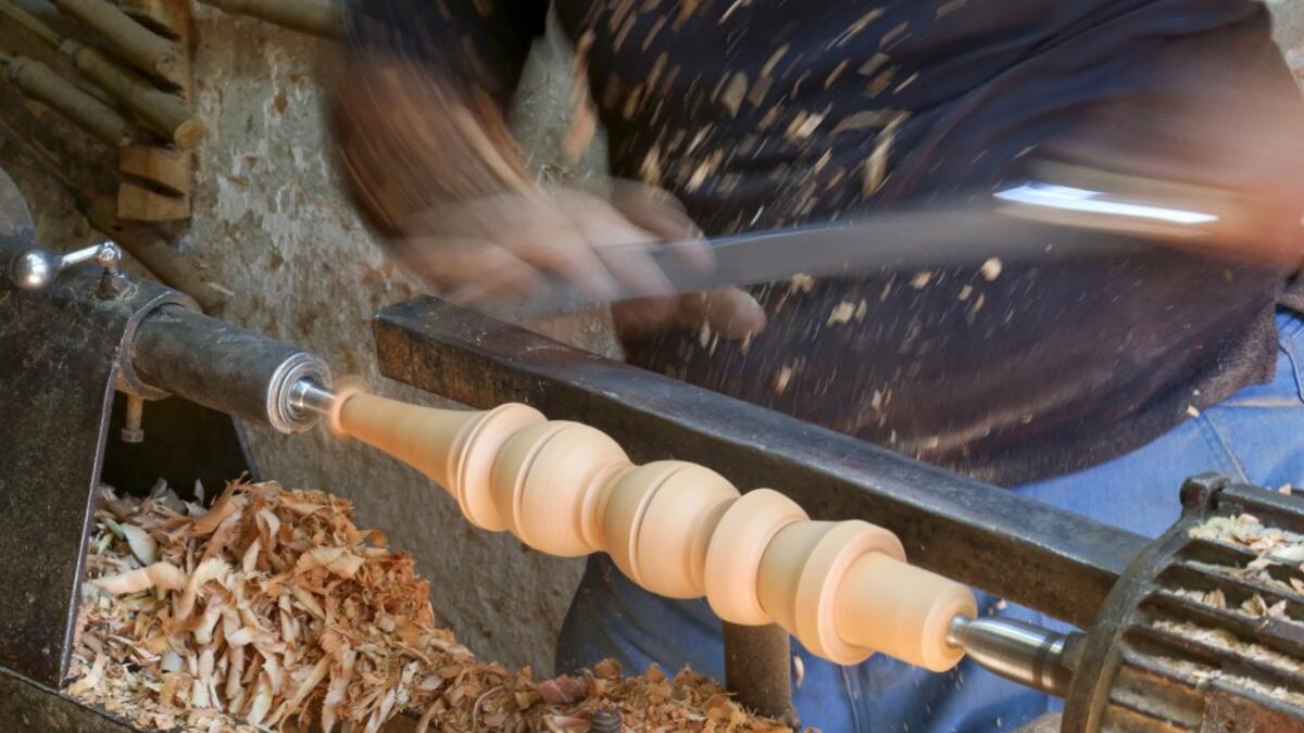 A carpenter shaves a piece of wood to make a narguileh (water pipe) at his workshop in Iraq's central holy city of Karbala on October 21, 2020. The business of strictly gender-separated cafes has carried on, despite the heavy health risks associated with smoking and a full-blown pandemic that has brought an average of 4,000 new coronavirus cases a day to Iraq. Mohammed SAWAF / AFP