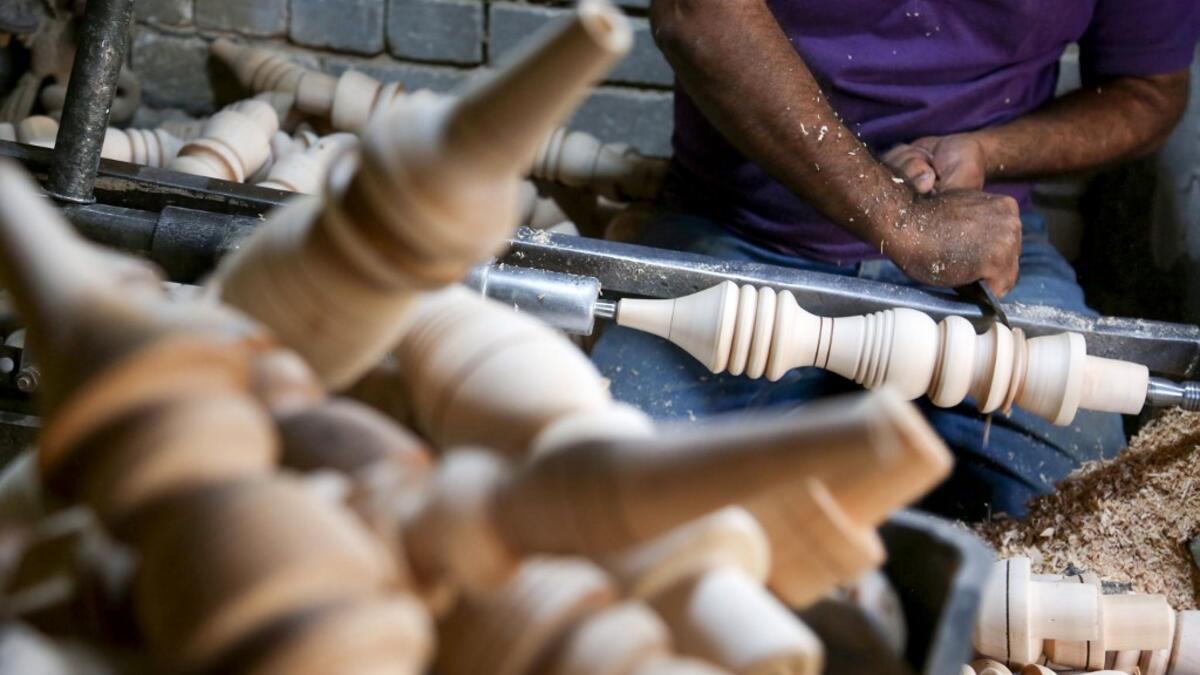 A carpenter shaves a piece of wood to make a narguileh (water pipe) at his workshop in Iraq's central holy city of Karbala on October 21, 2020. MOHAMMED SAWAF / AFP