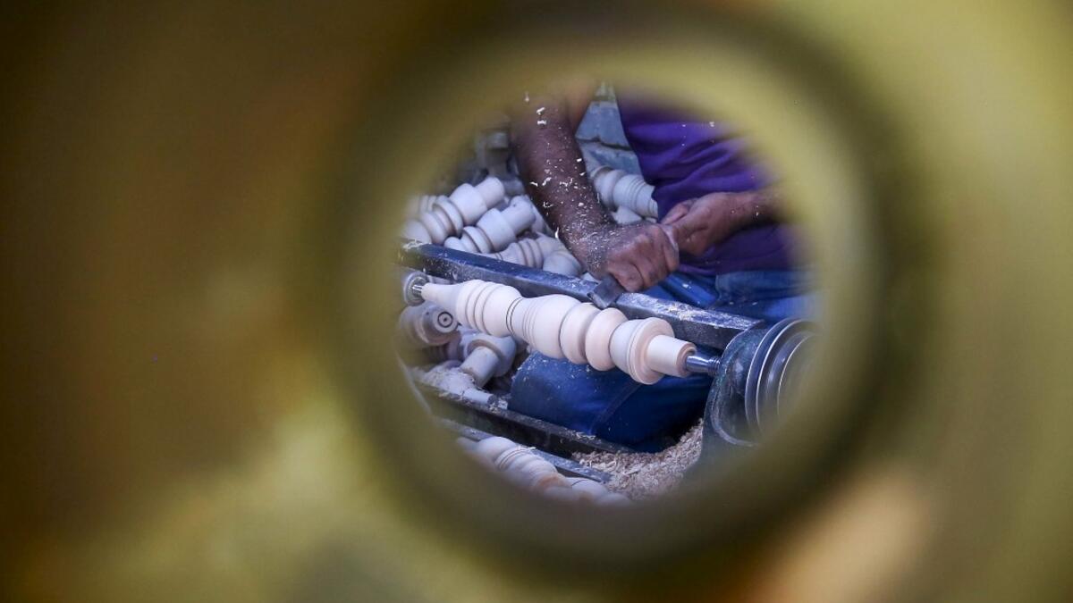 A carpenter shaves a piece of wood to make a narguileh (water pipe) at his workshop in Iraq's central holy city of Karbala on October 21, 2020. The business of strictly gender-separated cafes has carried on, despite the heavy health risks associated with smoking and a full-blown pandemic that has brought an average of 4,000 new coronavirus cases a day to Iraq. Mohammed SAWAF / AFP