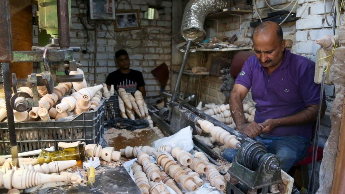 A carpenter shaves a piece of wood to make a narguileh (water pipe) at his workshop in Iraq's central holy city of Karbala on October 21, 2020. The business of strictly gender-separated cafes has carried on, despite the heavy health risks associated with smoking and a full-blown pandemic that has brought an average of 4,000 new coronavirus cases a day to Iraq. Mohammed SAWAF / AFP