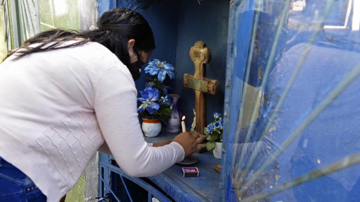 A woman lights a candle as she visits a relative's tomb at a cemetery in Asuncion on November 1, 2020, on All Saints' Day. Municipal cemeteries in Paraguay will be open to the public only on November 1 and 2, during All Saints' Day and the Day of the Dead, amid the new coronavirus pandemic. NORBERTO DUARTE / AFP
