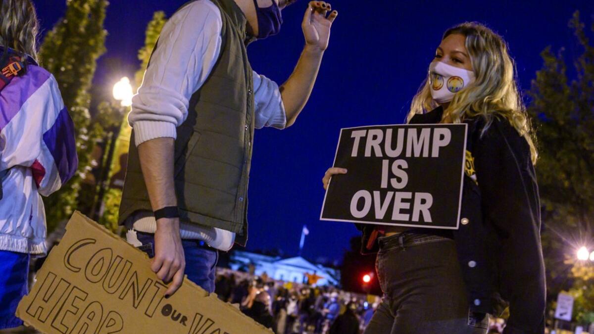 Young activists and Democratic party candidate supporters gather and dance on Black Lives Matter Plaza just outside of the White House (background) on November 4, 2020 in Washington DC. Democrat Joe Biden took a huge step Wednesday to capturing the White House, with wins in Michigan and Wisconsin bringing him close to a majority, but President Donald Trump responded with a diatribe alleging mass fraud and demanding a halt to vote counting. Eric BARADAT / AFP