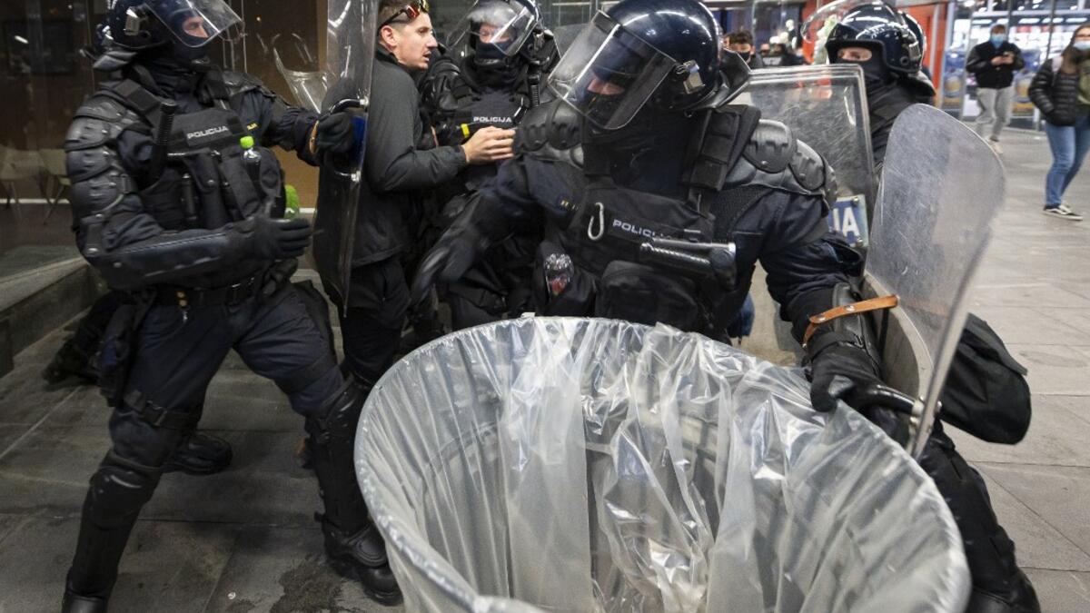 Police officers wearing riot gear grab a protester as they clash with police during the rally against government’s coronavirus restrictions in Ljubljana on November 5, 2020. Jure Makovec / AFP