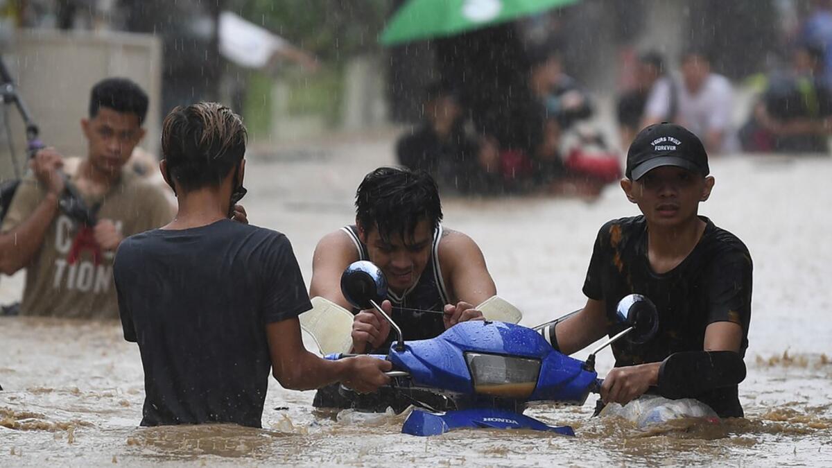 Residents carry their belongings as they make their way through a flooded street to shelter after Typhoon Vamco hit, in Marikina City, suburban Manila on November 12, 2020. Ted ALJIBE / AFP