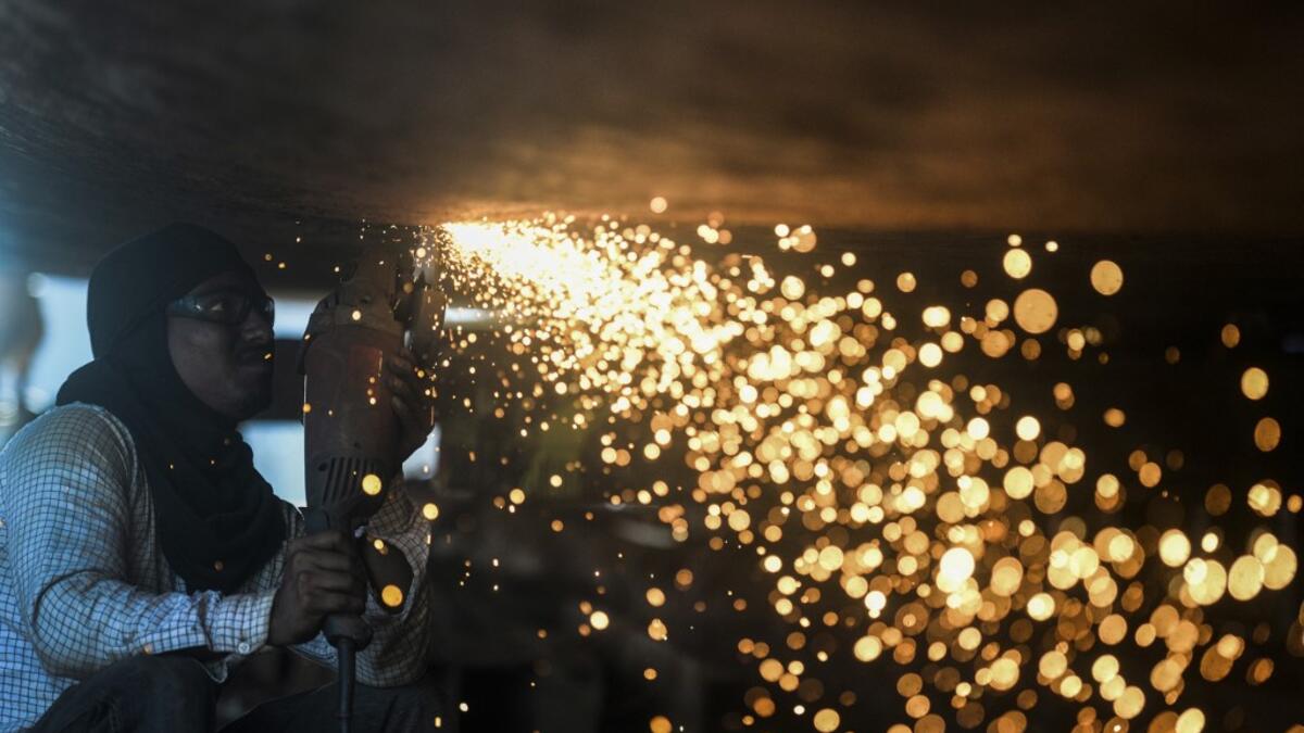 In this picture taken on November 11, 2020 a dockyard worker carries on maintenance works on the hull of a ship on the banks of the Buriganga River in Char Kaliganj on the outskirts of Dhaka. Rivers are the lifeblood of the delta nation of 168 million people where much of the low-lying land is accessed via boat, with Bangladesh's strong economic growth of recent years fuelling more investments in new and bigger ships. Munir UZ ZAMAN / AFP