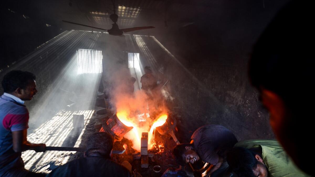 In this picture taken on November 12, 2020 dockyard workers pour molten iron in a mold to make a propeller at a workshop on the banks of the Buriganga river in Char Kaliganj on the outskirts of Dhaka. Rivers are the lifeblood of the delta nation of 168 million people where much of the low-lying land is accessed via boat, with Bangladesh's strong economic growth of recent years fuelling more investments in new and bigger ships. Munir UZ ZAMAN / AFP