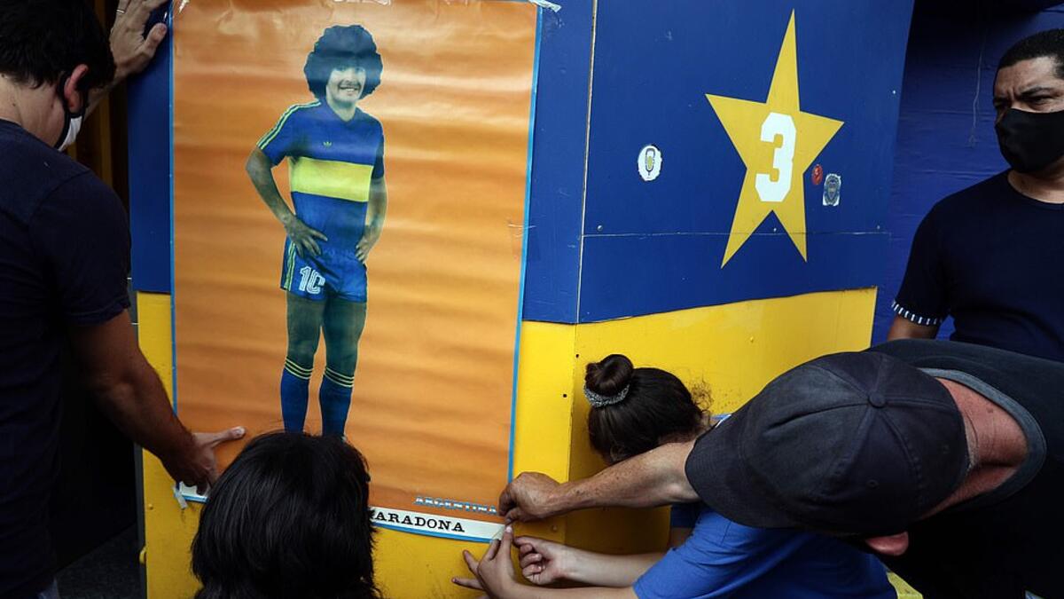 People hang a poster of the late Argentine football star Diego Maradona outside the Argentina's Boca Juniors La Bombonera stadium where people gather to mourn his death in Buenos Aires, on November 25, 2020. (AFP/File)