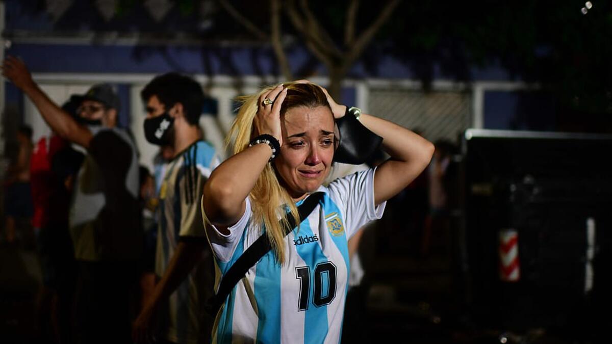 A woman wearing an Argentina number 10 shirt holds her head in grief as she gathers with other fans to pay tribute in Buenos Aires' La Paternal neighbourhood. (AFP/File)