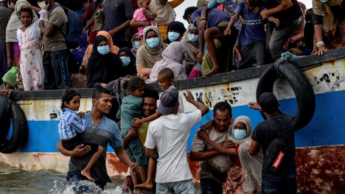 This photo taken on June 25, 2020 shows six-year-old daughter Nosmin Fatima (bottom L) being carried off a boat as she and her mother Majuma land with other Rohingya migrants in Lhokseumawe in North Aceh Regency. Weeks after a funeral for the wife and daughter he thought had died at sea while trying to sail to him, Nemah Shah was stunned when he saw online images of them emerging from a refugee boat in Indonesia. MUNIR UZ ZAMAN / AFP