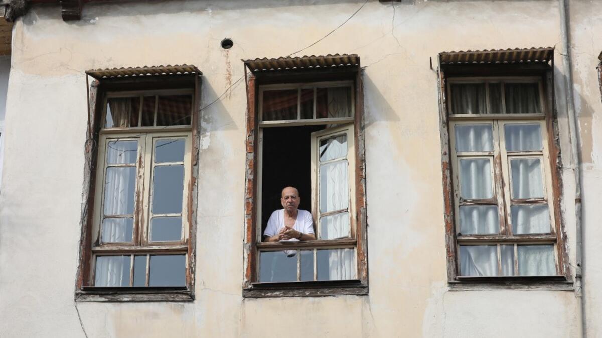 A man looks out the window in the old part of Syria's capital Damascus on October 28, 2020. The old city of the Syrian capital is famed for its elegant century-old houses, usually two storeys built around a leafy rectangular courtyard with a carved stone fountain at its centre. While the capital has been largely spared the violence of Syria's almost ten-year war, several of these traditional homes have been abandoned by their owners or damaged in the conflict. LOUAI BESHARA / AFP
