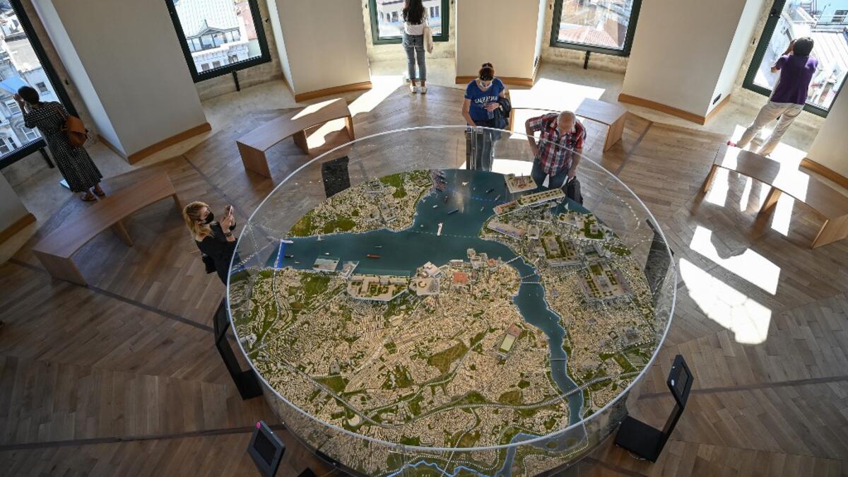 People look at a 3D Istanbul map after the restoration of the Galata Tower on October 16, 2020 in Istanbul. The Galata Tower -- an emblematic 14th century monument of Istanbul -- has become the latest victim of such controversy. The demolition of one of its walls with a jackhammer as part of a restoration work was narrowly avoided last August after a video leaked on social media, which sparked strong criticism from the largest city's residents. Ozan KOSE / AFP