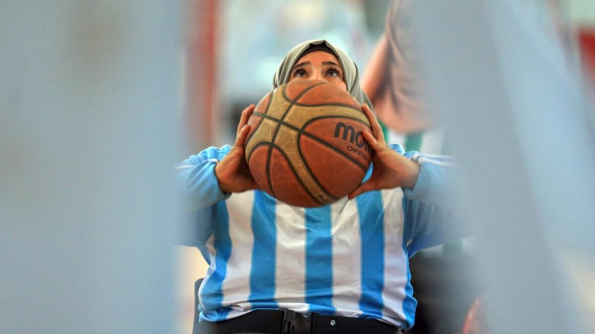 A disabled Yemeni woman prepares to shoot the ball during a local wheelchair basketball championship in Yemen's capital Sanaa on December 8, 2020. In conflict-ridden Yemen, nine teams, including five-all women groups, competed in a local championship for the disabled in the capital Sanaa, which has been under rebel control since 2014. The players are competing to be embraced by society for their strengths rather than be viewed as a burden during the time of war. Mohammed HUWAIS / AFP