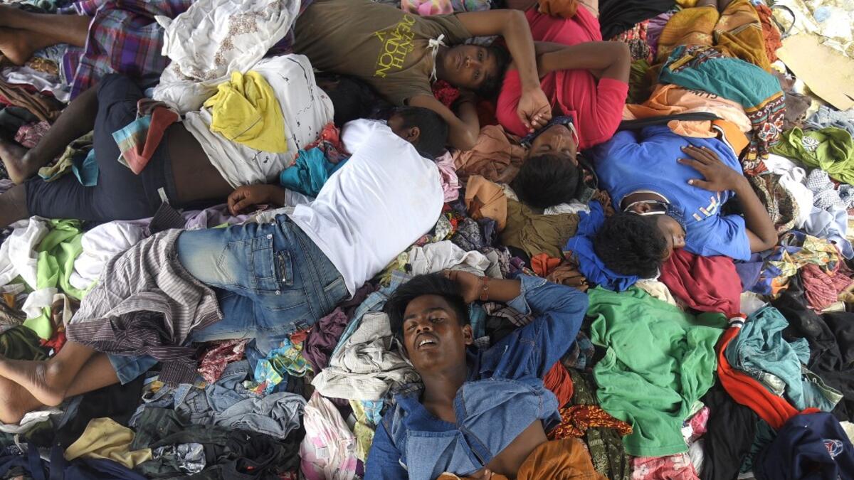 This file picture taken on September 8, 2020 shows a group of Rohingya men sleeping on a pile of donated clothes at a transit camp after nearly 300 Rohingya migrants came ashore on the beach in Lhokseumawe on the northern coast of Indonesia's Sumatra island. Boatloads of Rohingya landing across Southeast Asia are victims of complex human trafficking networks run by a dizzying web of players, from crime bosses and corrupt cops to poor fishermen, rickshaw drivers and even Rohingya themselves. Rahmat Mirza / A