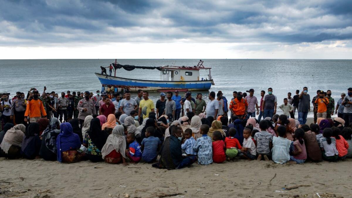 In this file photo taken on June 25, 2020 Rohingya migrants sit by the beach after their boat landed on the shores of Lancok village, in Indonesia's North Aceh Regency. Boatloads of Rohingya landing across Southeast Asia are victims of complex human trafficking networks run by a dizzying web of players, from crime bosses and corrupt cops to poor fishermen, rickshaw drivers and even Rohingya themselves. CHAIDEER MAHYUDDIN / AFP
