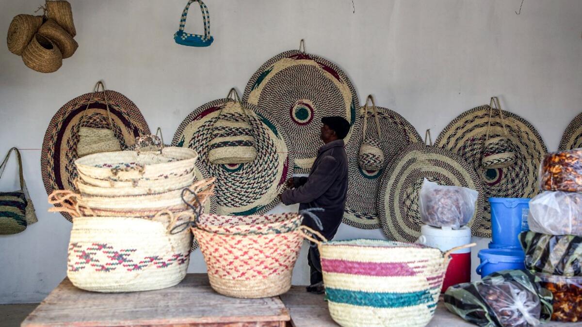 A man inspects palm wicker products on display, made by Haleema Mohamed, one of the residents who returned to the city of Tawergha after fleeing in the aftermath of the toppling of Kadhafi, sits making palm wicker products at a home in Tawergha, some 200 kilometres (125 miles) east of Libya's capital close to the port city of Misrata, on December 12, 2020. When Libyan dictator Moamer Kadhafi was toppled, people took revenge on those they saw as his supporters -- including the entire town of Tawergha, whose