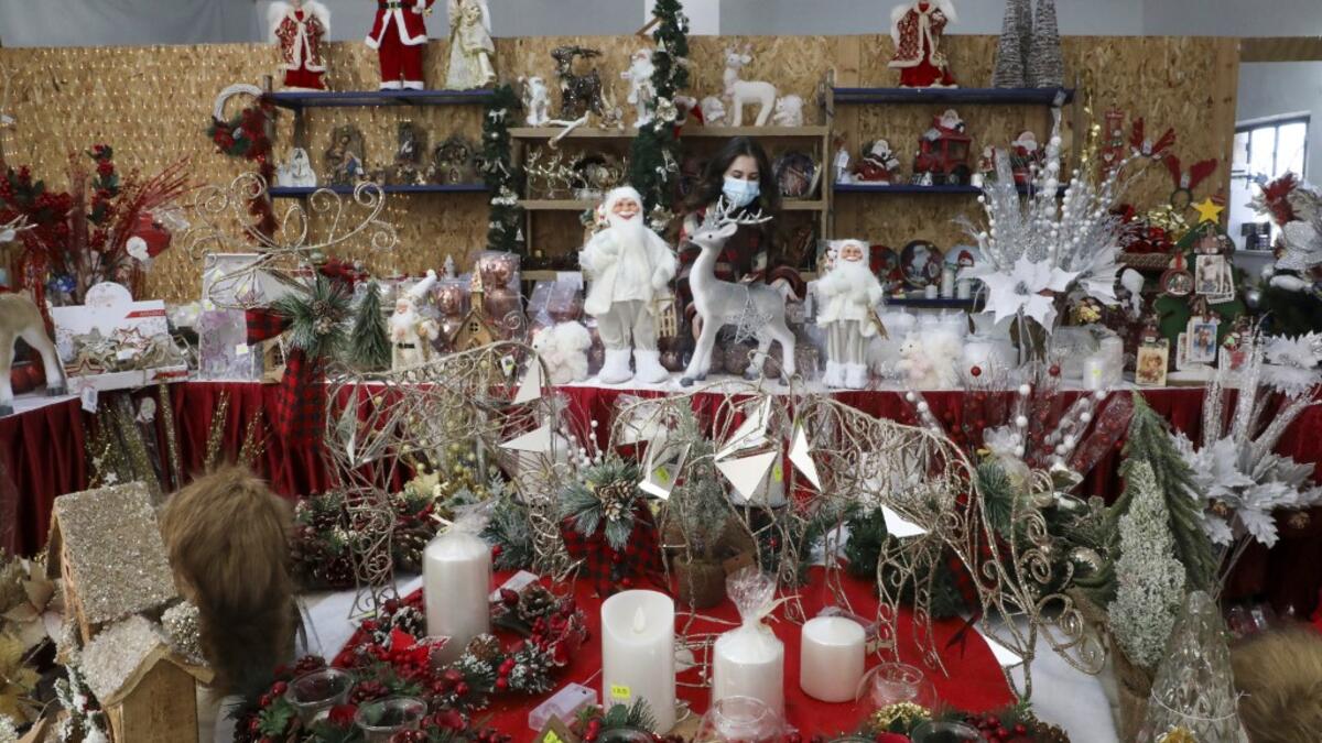 A Palestinian shop-owner arranges Christmas decorations at her shop in the West Bank city of Bethlehem on December 21, 2020. HAZEM BADER / AFP