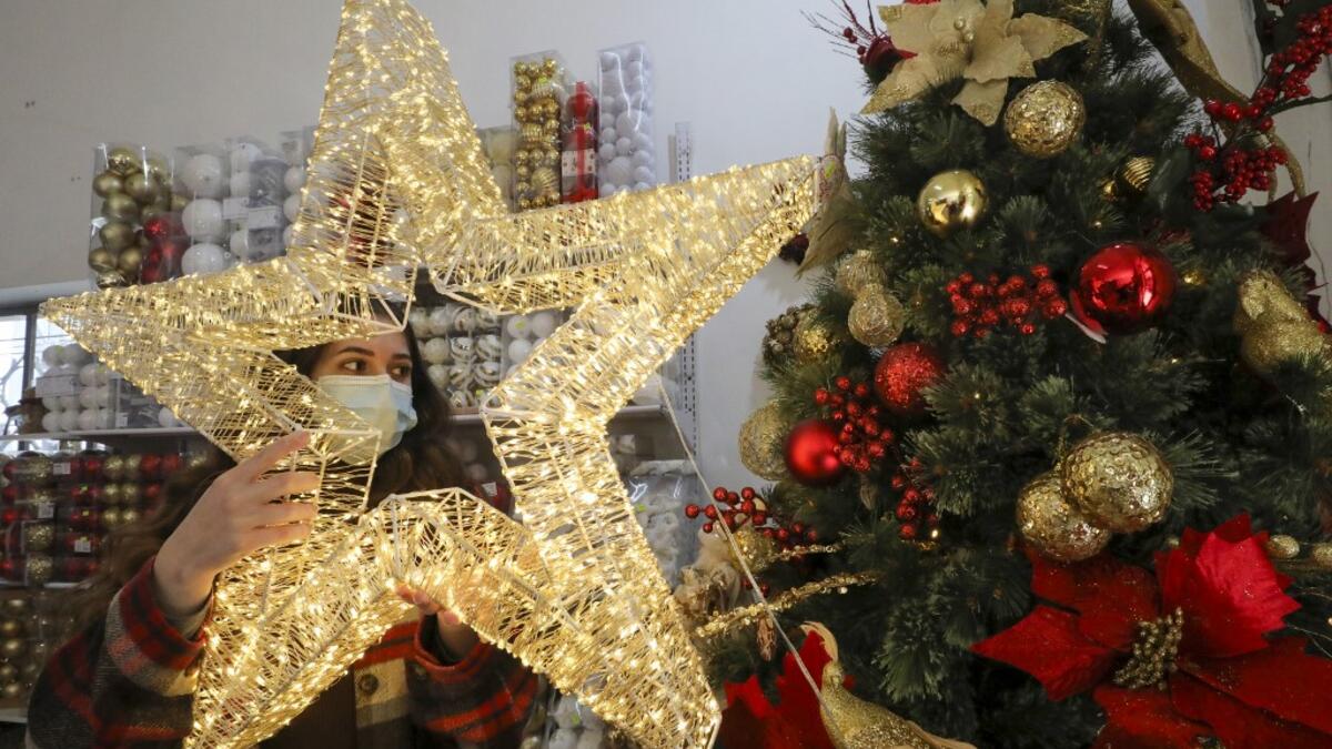 A Palestinian shop-owner arranges Christmas decorations at her shop in the West Bank city of Bethlehem on December 21, 2020. HAZEM BADER / AFP