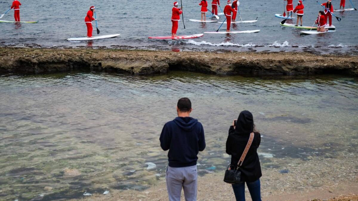 Lebanese people dressed in Santa Claus outfits ride on standup paddles in Lebanon's northern coastal city of Batroun on December 22, 2020. Ibrahim CHALHOUB / AFP