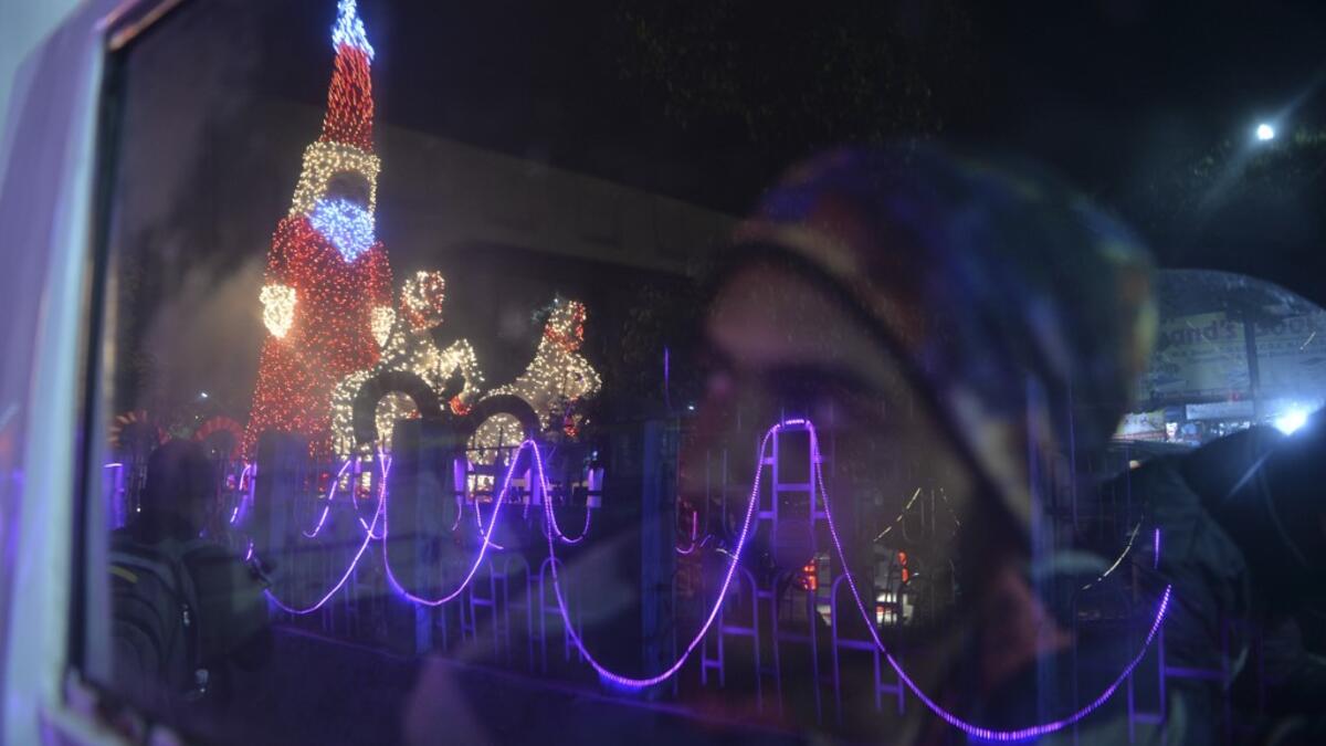 A car driver looks at a model of Santa Claus illuminated, on the eve of Christmas in Siliguri on December 24, 2020. DIPTENDU DUTTA / AFP