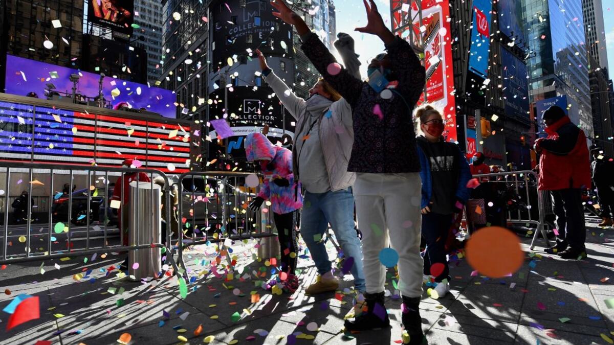 People play with confetti as New Year's Eve organizers test the air worthiness of confetti from the Hard Rock Cafe Marquee in Times Square on December 29, 2020 in New York City. The 2,000 pounds of confetti (907 kilograms) released on New Year’s Eve will include thousands of wishes from individuals who have submitted them at the New Year’s Eve Wishing Wall. Angela Weiss / AFP