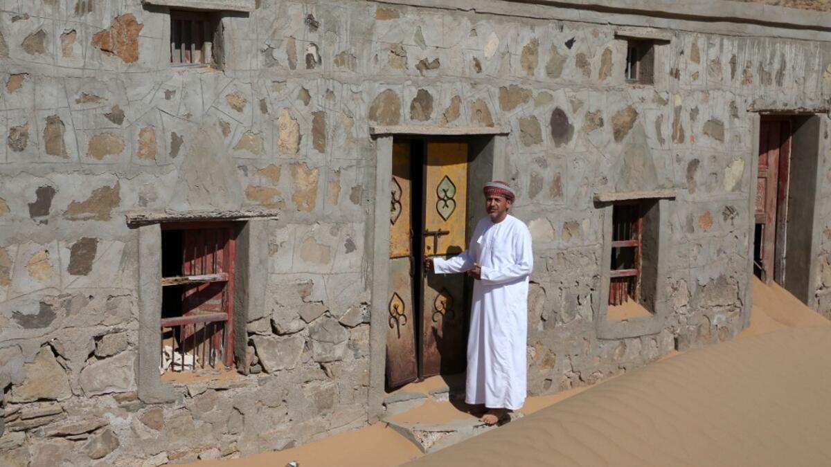Mohammed al-Ghanbousi, a former inhabitant of Wadi al-Murr, stands next to his abandoned house in the Omani village, about 400 kms (250 miles) southwest of the capital Muscat, on December 31, 2020. Encroaching desert sands have left little evidence that Wadi al-Murr ever existed, but former inhabitants, while resigned to its destruction, are trying to preserve its memory. MOHAMMED MAHJOUB / AFP