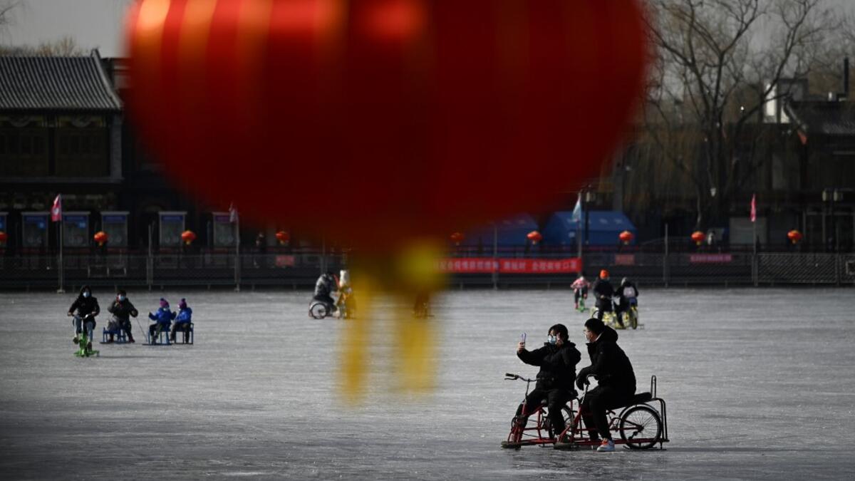 A man and a woman use a mobile phone to take a selfie as they ride sled on a frozen lake in Beijing on January 12, 2021. WANG Zhao / AFP