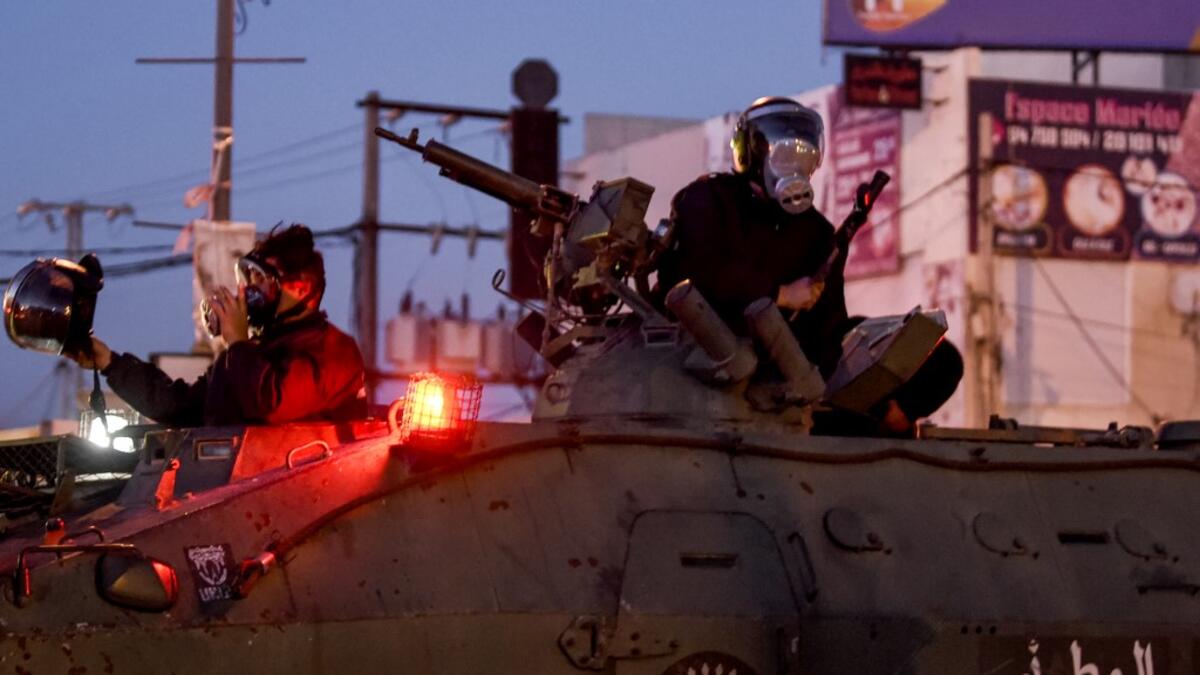 Members of Tunisia's National Guard sit atop an armoured personnel carrier preparing for clashes with protesters in the Ettadhamen city suburb on the northwestwern outskirts of Tunisia's capital Tunis on January 17, 2021, amidst a wave of nightly protests in the North African country. FETHI BELAID / AFP