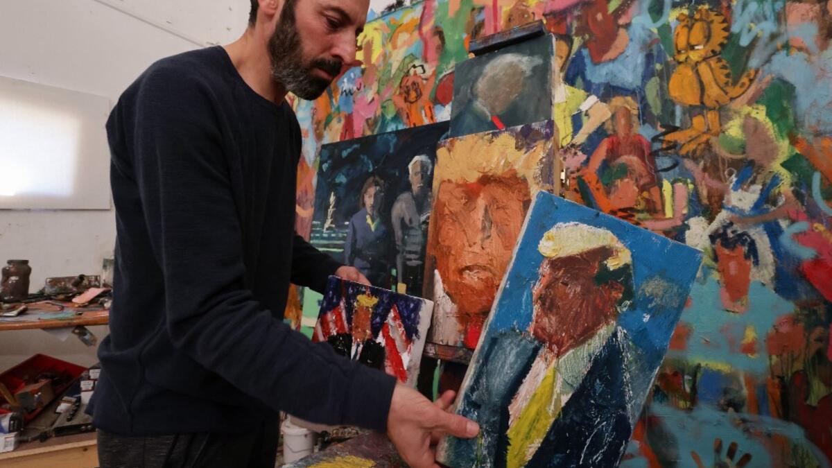 Israeli painter Iddo Markus arranges his paintings of former US president Donald Trump, at his studio in the northern port city of Haifa, on January 22, 2021. Markus became fascinated by the "tragic figure" of Donald Trump, and the walls and floor of his studio are packed with some 120 portraits of the former US presidents. Emmanuel DUNAND / AFP