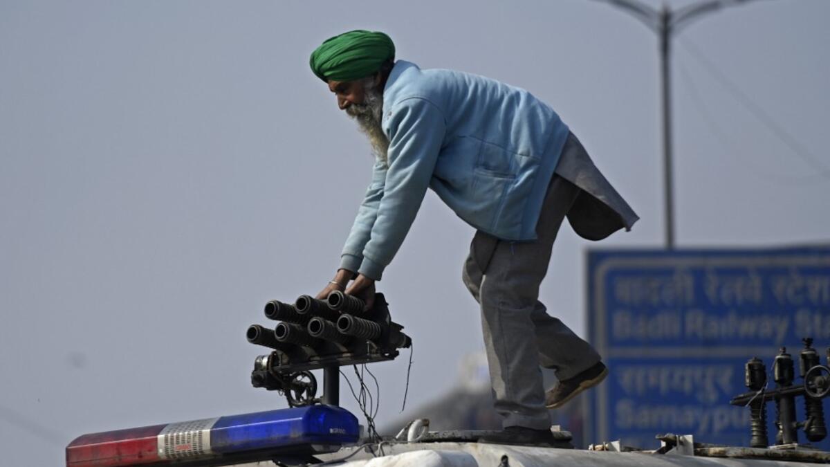 A farmer stands on a police vehicle during a tractor rally as farmers continue to demonstrate against the central government's recent agricultural reforms in New Delhi on January 26, 2021. Money SHARMA / AFP