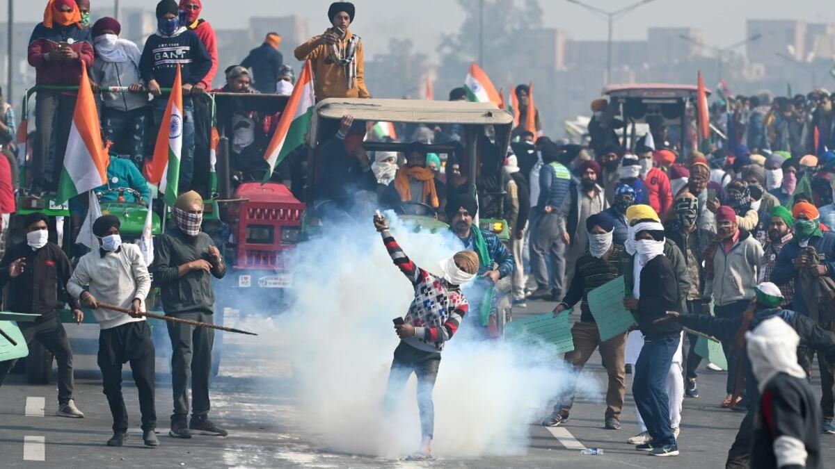 A farmer throws back a tear gas shell fired by the police to disperse them during a tractor rally as farmers continue to demonstrate against the central government's recent agricultural reforms in New Delhi on January 26, 2021. Sajjad HUSSAIN / AFP