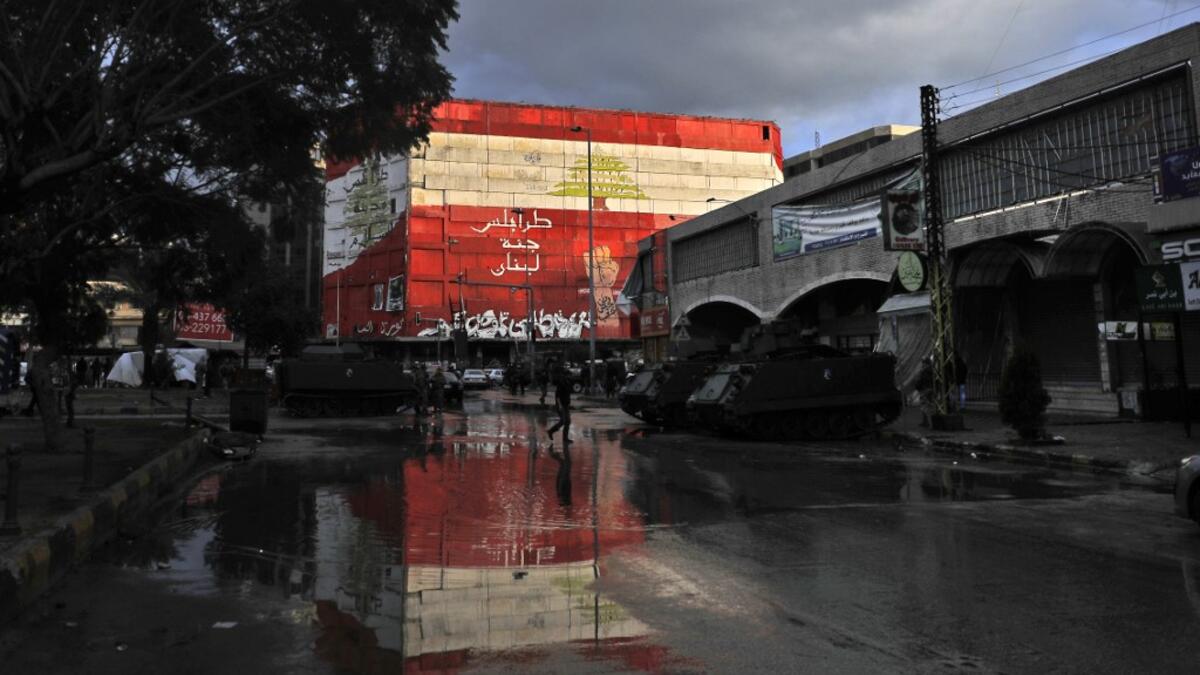 A picture taken on January 29, 2021 shows armoured personnel carriers parked under a mural in Al-Nour square in the Lebanese northern city of Tripoli, following overnight clashes between security forces and anti-government protests. More than 400 people have been wounded in northern Lebanon this week in clashes between security forces and protesters angered by a coronavirus lockdown they say is starving them. JOSEPH EID / AFP