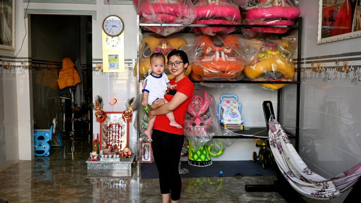 This photograph taken on January 20, 2021 shows Le Yen Quyen posing with her one-year-old daughter before leaving for practice at the Tu Anh Duong lion and dragon dance school in Can Tho city in southern Vietnam's Mekong Delta. Manan VATSYAYANA / AFP