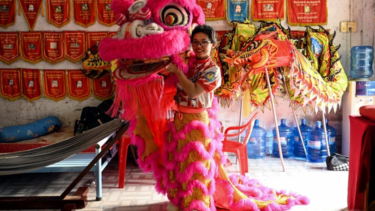 This photograph taken on January 20, 2021 shows Le Yen Quyen posing with her lion dance mask before a practice session at the Tu Anh Duong lion and dragon dance school in Can Tho city in southern Vietnam's Mekong Delta. Manan VATSYAYANA / AFP