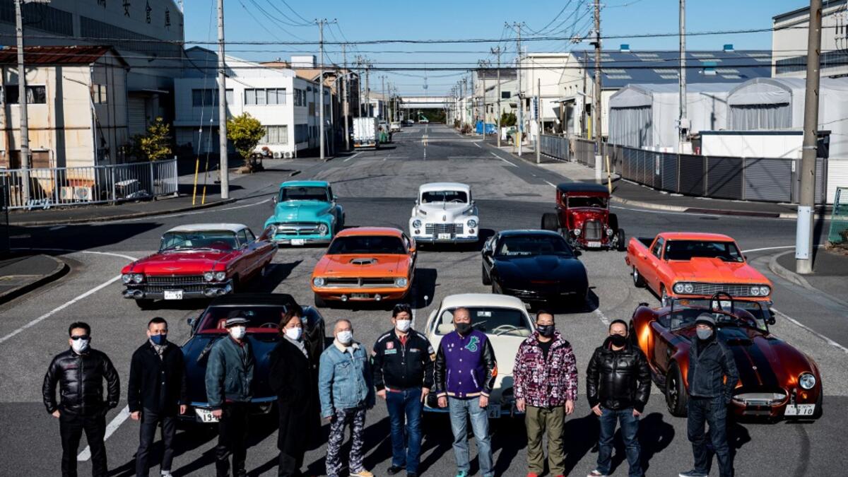 This picture taken on January 31, 2021 shows car owners posing for a photo during a gathering of auto enthusiasts in Urayasu, an eastern suburb of Tokyo. A loose club of fans rolls up most weekends in central Tokyo to show off their Cadillacs, Chevrolets and other modern classic vehicles from the mid to late 20th century. Philip FONG / AFP