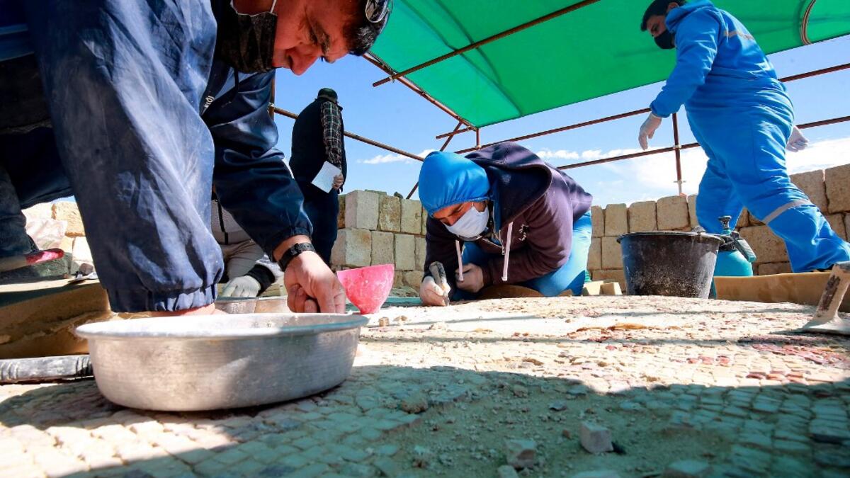 Workers employed by a pilot project run by the UN cultural agency UNESCO, restore a mosaic floor at an ancient church complex, in the small town of Rihab, some 70 kilometres north of the Jordanian capital Amman, on February 9, 2021. In the ruins of the ancient Byzantine church in Jordan, local townspeople and Syrian refugees work side by side on a project that unites preserving cultural heritage and fighting poverty.  Khalil MAZRAAWI / afp