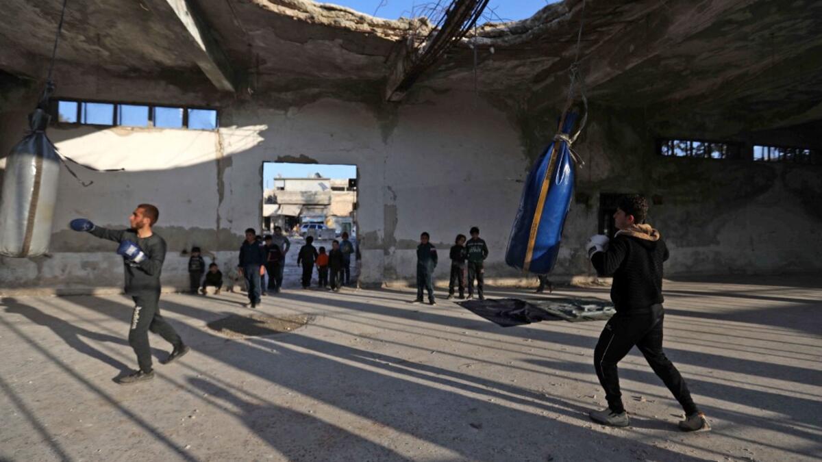 Syrian youths take part in a boxing workout held by local boxer Ahmad Dwara (unseen) inside a damaged building in the town of Atareb in the rebel-held western countryside of Syria's Aleppo province, on February 11, 2021. AAREF WATAD / AFP