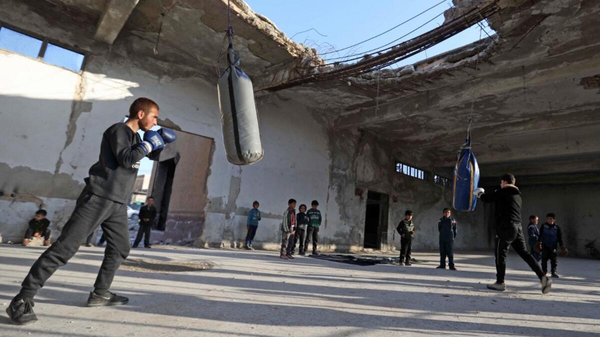 Syrian youths take part in a boxing workout held by local boxer Ahmad Dwara (unseen) inside a damaged building in the town of Atareb in the rebel-held western countryside of Syria's Aleppo province, on February 11, 2021. AAREF WATAD / AFP