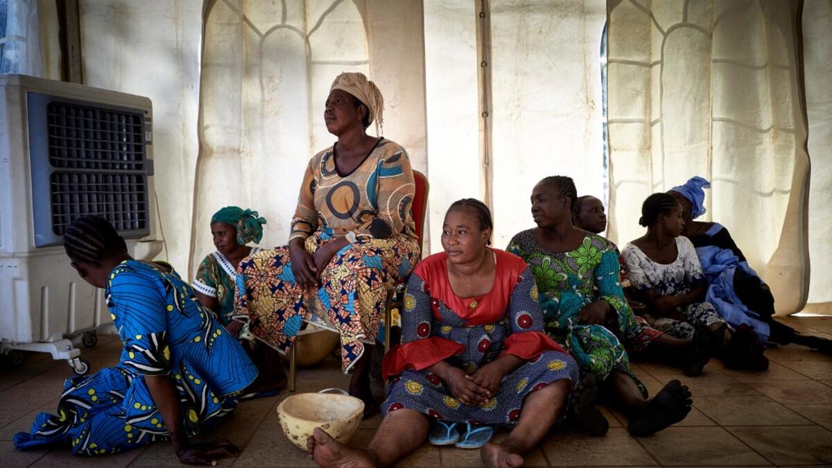 A group of gold miners site on the floor in the backstage after having been selected by the Princess of Burundi, Esther Kamatari, to take part in a fashion show as part of the first edition of the International Gold Fair Afrik'Or, in Bamako, on February 12, 2021. The Princess of Burundi, selected 34 women among gold mines workers in southern Mali, to walk down the catwalk for a fashion show organised during the International Gold Fair. Gold represents 15% of Mali's exports and more than 20% of its GDP estim