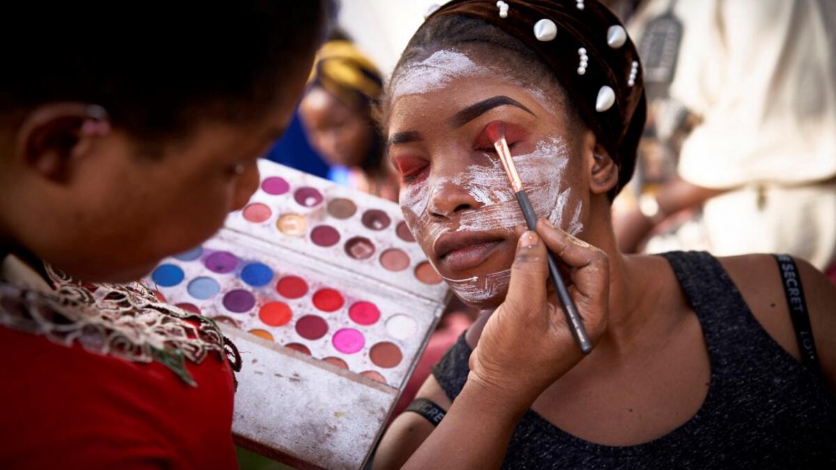 A make up artist gets a model ready, in the backstage, prior to take part, in a fashion show as part of the first edition of the International Gold Fair Afrik'Or, in Bamako, on February 12, 2021. The Princess of Burundi Esther Kamatari, selected 34 women among gold mines workers in southern Mali, to walk down the catwalk for a fashion show organised during the International Gold Fair. Gold represents 15% of Mali's exports and more than 20% of its GDP estimated at nearly US$20 billion by the end of 2019. MIC