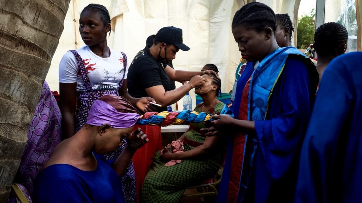 Gold miners are helped to get ready in the backstage prior to take part in a fashion show as part of the first edition of the International Gold Fair Afrik'Or, in Bamako, on February 12, 2021. The Princess of Burundi Esther Kamatari, selected 34 women among gold mines workers in southern Mali, to walk down the catwalk for a fashion show organised during the International Gold Fair. Gold represents 15% of Mali's exports and more than 20% of its GDP estimated at nearly US$20 billion by the end of 2019. MICHEL