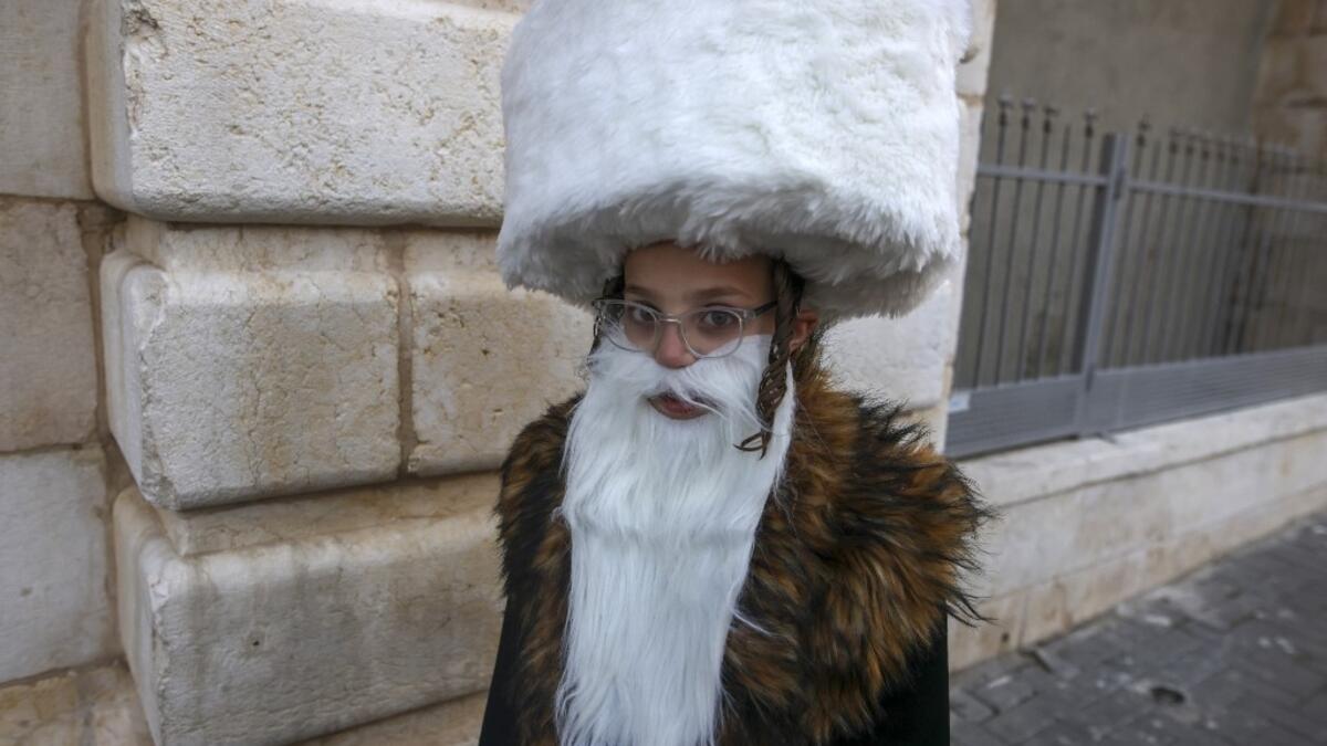An Ultra-Orthodox Jewish child, wearing a fake beard and a shtreimel to celebrate Purim, walks in Jerusalem's the Mea Shearim neighborhood in, on February 25, 2021. Israel imposed a night-time curfew for three nights to curb the spread of the coronavirus during the Jewish holiday of Purim. The carnival-like Purim holiday is celebrated with parades and costume parties to commemorate biblical story of the deliverance of the Jewish people from a plot to exterminate them in the ancient Persian empire, as record